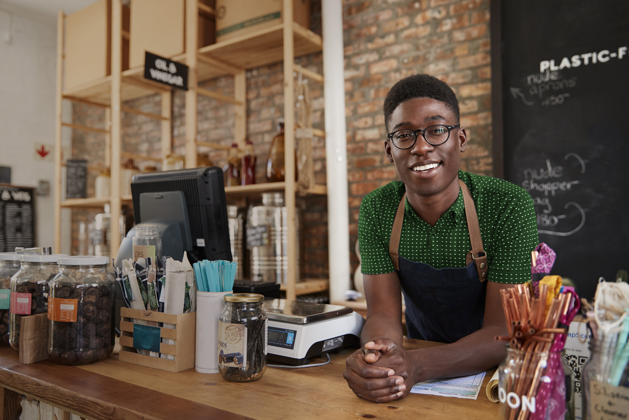 Portrait Of Male Owner Of Sustainable Plastic Free Grocery Store Behind Sales Desk